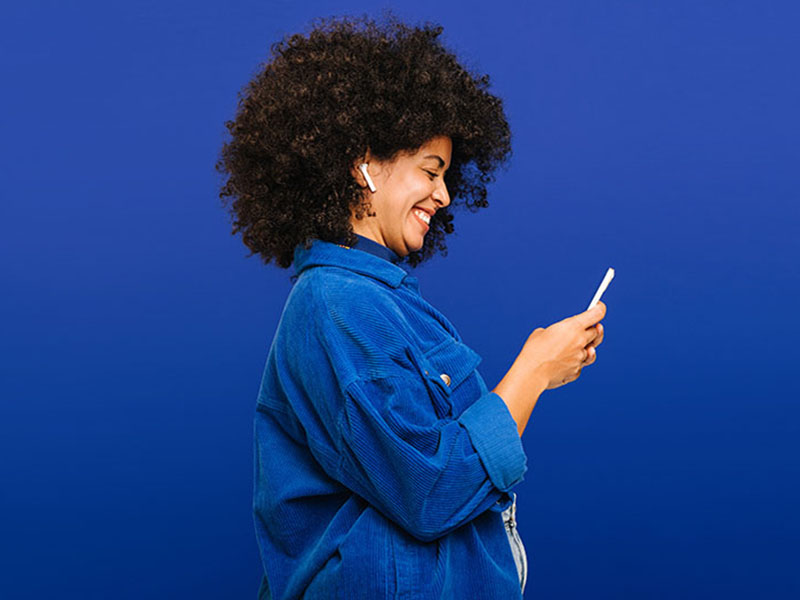 Carefree young woman playing music using a smartphone and earbuds
